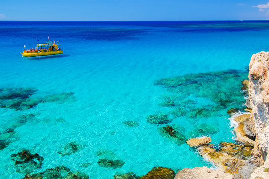 Tourist boat on azure sea water near Cavo Greko peninsula, Cyprus island