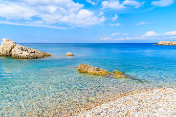 Beautiful pebble stone beach with rocks in Kokkari village on sunny summer day, Samos island, Greece