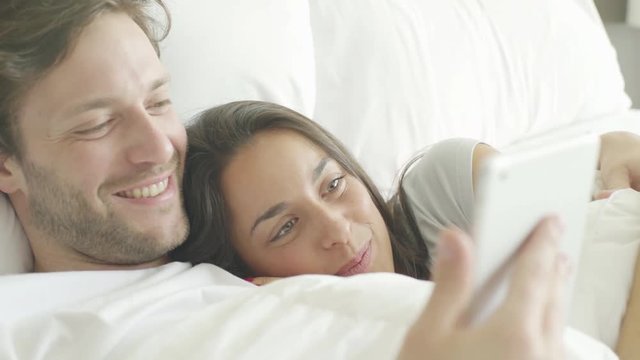 Couple using wireless device in bed