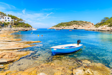 Small fishing boat on shore Cala Portinatx bay, Ibiza island, Spain