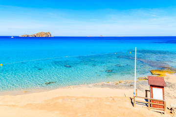 Fototapeta na wymiar Lifeguard tower on beautiful Cala Comte beach famous for its azure crystal clear shallow sea water, Ibiza island, Spain