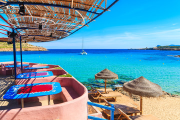 View of Cala Comte beach with sunbeds and umbrellas on shore, Ibiza island, Spain