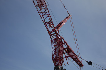 Red industrial construction crane against blue sky with copy space