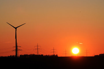 Fototapeta na wymiar Windrad mit Strommast und Hochspannungsleitungen im Abendrot, Sonnenuntergang