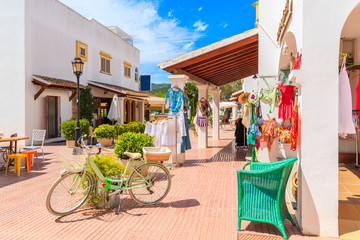 Green classic bicycle decorated with spring flowers on square with shopes in Sant Carles de Peralta village, Ibiza island, Spain