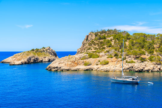 Sailing boat on blue sea water in Cala Salada bay, Ibiza island, Spain