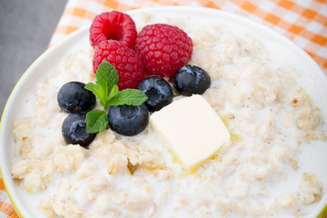 Oatmeal porridge in bowl with berries raspberries and blackberries.