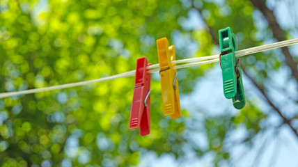 Red, yellow, green clothespins on a rope on a nature background