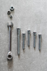 Construction tools. The screws, nuts and bolts on concrete background. Repair, home improvement concept. Top view, flat lay.