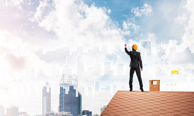 Man architect draw silhouette of modern city on blue sky. Mixed media
