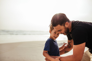 Young man with his son at the beach - Powered by Adobe