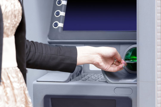 Close up hand inserting card into ATM