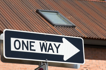 One way sign with arrow in front of corrugated roof