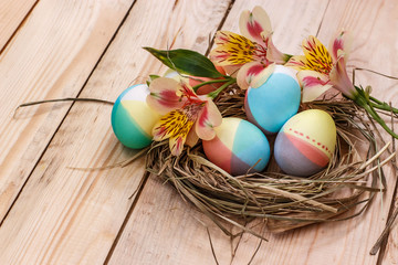 Easter eggs in straw nest on a light wooden background