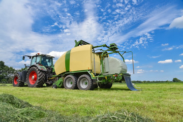 Grasernte , Traktor mit Großballenpresse und Folienwickler im Einsatz