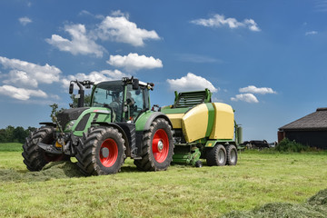 Ernte - Traktor mit Großballenpresse vor blauem Himmel