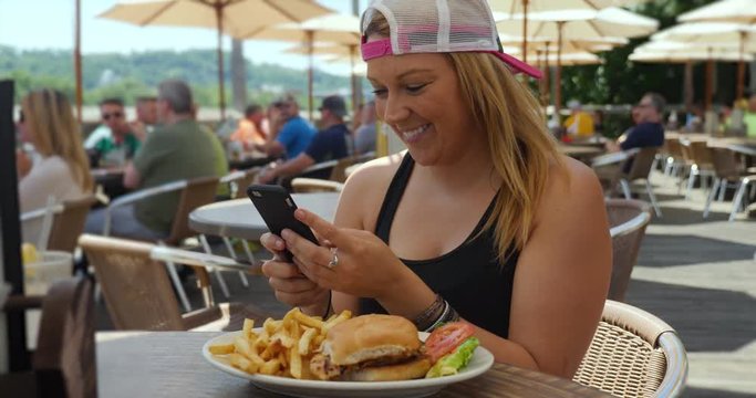 A young millennial takes a picture of her lunch then posts on social media. Outside restaurant or cafe location.  	