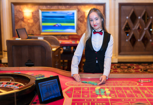 Cute Lady Casino Dealer At Roulette Table.