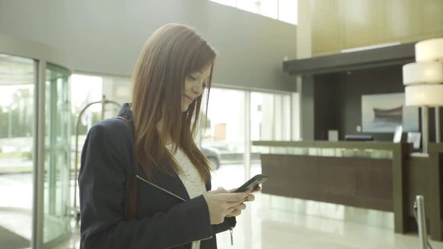 Woman using smartphone in hotel lobby