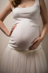 Closeup of young pregnant woman's belly. Expecting a baby. Motherhood and childhood.