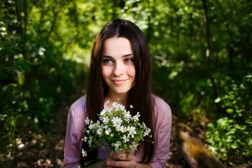 Young cute smiling woman with a bouquet of petite forest flowers