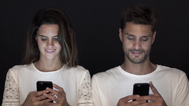 Couple side by side, both engrossed in their smartphones