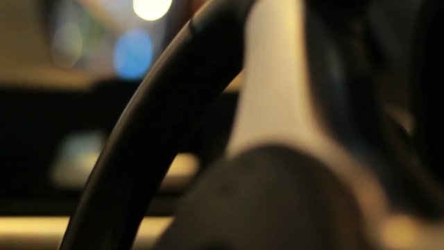 Car steering wheel. Close up of leather steering wheel turning. Driving in city at night. Car wheel rotation. Closeup of car steering wheel. Night drive