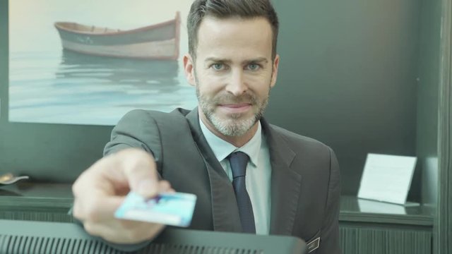 Hotel receptionist handing credit card to customer