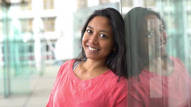 Woman leaning against window, smiling, portrait