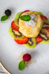 Close-up of a trendy dessert, fried ice cream with kiwi and strawberries, raspberries and blackberries, decorated with mint, sweet delicious, beautiful serve, restaurant