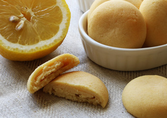 Fresh lemon and assorted white lemon cookies whole and sliced on grey linen cloth background