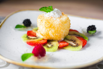 Close-up of a trendy dessert, fried ice cream with kiwi and strawberries, raspberries and blackberries, decorated with mint, sweet delicious, beautiful serve, restaurant