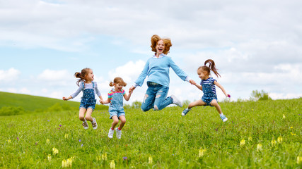 Fototapeta premium Happy family mother and children daughter girls laughing and jump on meadow in summer