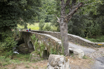 pilgrims on the Ponte Áspera medieval bridge over Pequeño river, Sarria, province of Lugo,...