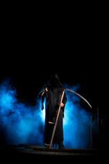 grim reaper with scythe and blue smoke at night pointing finger
