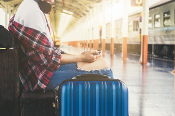 Alone travler with headphone and suitcase and cell phone at railway platform in summer, alone travel concept.