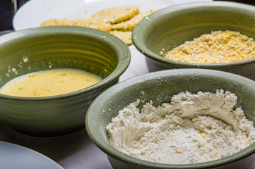 Applying cornmeal dredge to tomato slices