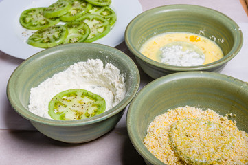 Applying cornmeal dredge to tomato slices