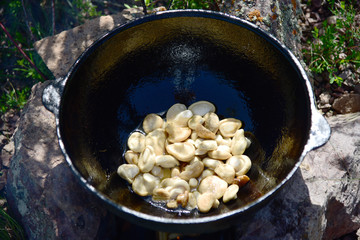 Cooking frying muchrooms in oil on the bonfire outdoor
