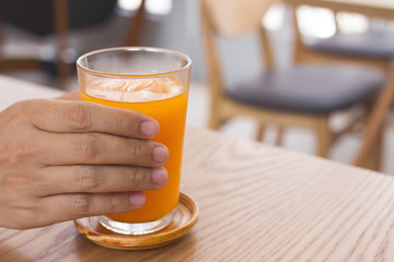 Man hand holding a glass of orange juice.