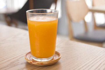 A glass of orange juice on wooden table.