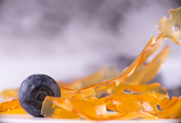 Marijuana oil concentrate aka shatter on a plate with with blueberries