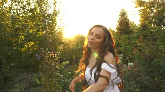 Young cute girl with long hair dancing. Sunset sun in the garden. Happiness and freedom.