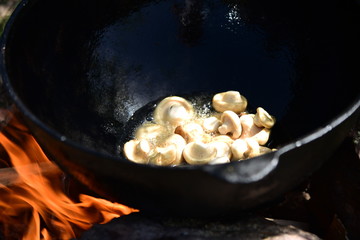 Cooking frying muchrooms in oil on the bonfire outdoor