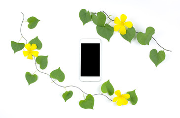 Smart phone with heart shape leaves and flowers frame on white background. Flat lay