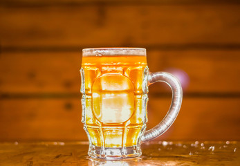 Close up of a blonde craft beer filled into a pint glass on wooden background
