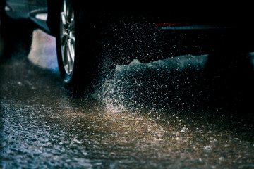 Motion car in rain big puddle with water splashing from the wheels