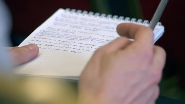 Male hand with pen and exercise book. Twirls a pen (close-up)