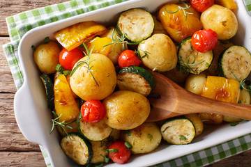 Obraz na płótnie Canvas Vegan food: potatoes baked with zucchini, pepper and tomatoes close-up in baking dish. horizontal top view