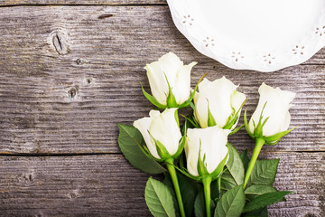 A bouquet of white tea roses on a simple rustic gray wooden background. Top view. Romantic picture